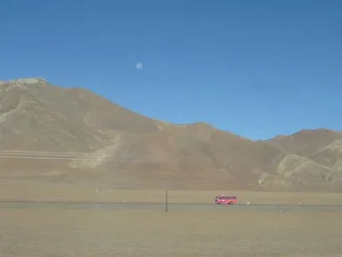 広大な大地を走るピンクのバスが見える青蔵鉄道の車窓