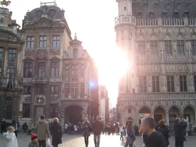 ブリュッセルのグラン・プラスの建物のすき間から夕日が差し込む光景