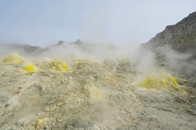 硫黄山の黄色い硫黄の岩から白い煙が噴出される様子