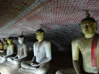 ダンブッラ石窟寺院の金の仏像が並び壁には仏画が描かれる景色