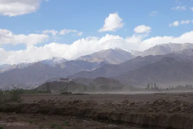 遠くから見た丘の上のスタクナゴンパと周りの山々の風景