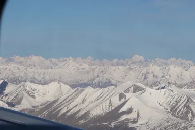 飛行機の窓から幾重にも空へ伸びるヒマラヤの姿