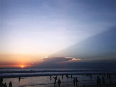 ビーチに沈む夕日と雲の影が空へと伸びる