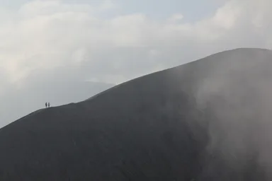 ブロモ山の火口の細いふちを歩く人