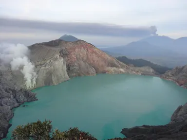 青緑のイジェン火口湖と硫黄の煙と遠くの火山が噴火している景色の見どころ