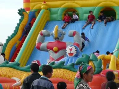 ポーンサワンのお祭りでウルトラマンやドラえもんの巨大遊具で遊ぶ子供たちの姿